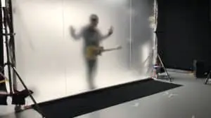 U2 band member behind a large diffusion screen, creating a ghostly silhouette while playing guitar for 2018 tour video, managed by Films.Solutions.