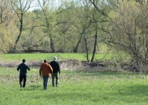 The director, DOP, and a local drone operator walking towards the crime scene, engaged in discussion.