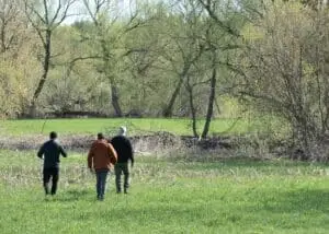 The director, DOP, and a local drone operator walking towards the crime scene, engaged in discussion.