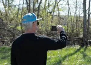 The director, capturing the scene with his iPhone, immersed in the visual storytelling of the crime scene.