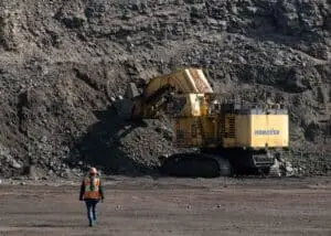 Mining specialist walking towards a giant hydraulic mining shovel in a mine in Labrador City