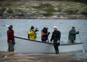 Team and two brothers, participants from a family business, near a white boat making last preparations for departure on the north-shore of Québec