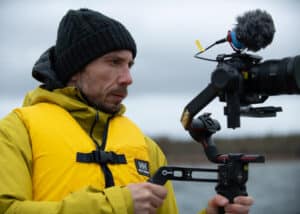 Cinematographer in a yellow safety vest, concentratedly filming with his camera on a gimbal