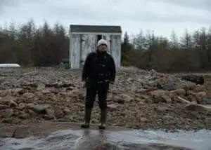One of the brothers, posing fashionably in a FAY jacket on the shore, amidst foggy and slightly rainy weather