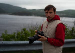 Marco, the cinematographer, handling his camera with the Saguenay River in Quebec in the background
