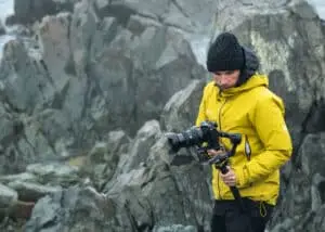 Cinematographer carefully walking on a difficult rocky path to reach the next filming location