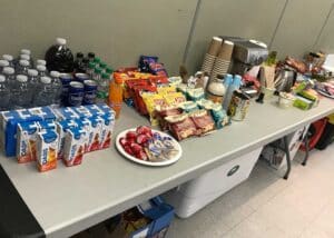 A well-stocked craft table with a variety of food, coffee, energy bars, and drinks for technicians.