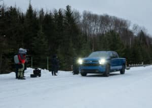 Film crew preparing on the side of a street in a Quebec National Park, with a blue GMC pickup truck passing by for the initial take.
