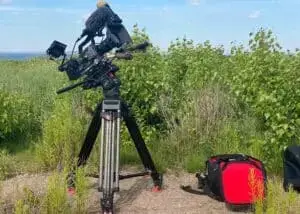 A Sony FX9 camera perched on a tripod, stationed in an expansive field, capturing scenic views during the journey to Nova Scotia for 'Race Across the World 3'