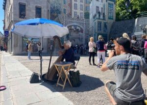 A cameraman from the 'Race Across the World 3' team films a street musician in Québec City.